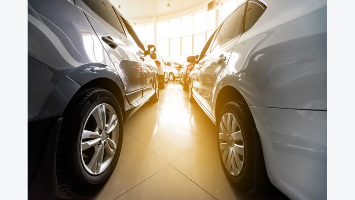 Autos stehen im Autohaus, Sonne scheint durch die Fenster des Autohauses