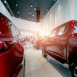 Rear view of red car parked in luxury showroom. Car dealership office. New car parked in modern showroom. Car for sale and rent business concept. Automobile leasing and insurance. Closeup tail light.