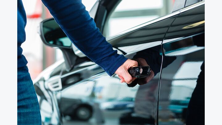 Young man beside a new car in car dealership, obviously he is buying the auto, or making a test drive