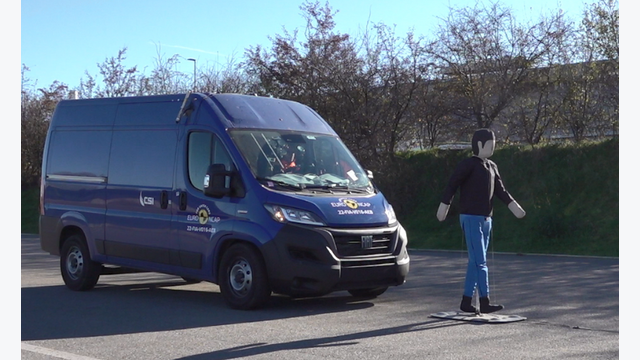 Ein Transporter fährt frontal auf einen Dummy zu, der einen Fußgänger simuliert