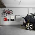 Electric black vehicle using electric car charging station at home. Particular Electric Vehicle Charging Station at home garage with bicycle hanging on the wall. Copy-space, Horizontal.