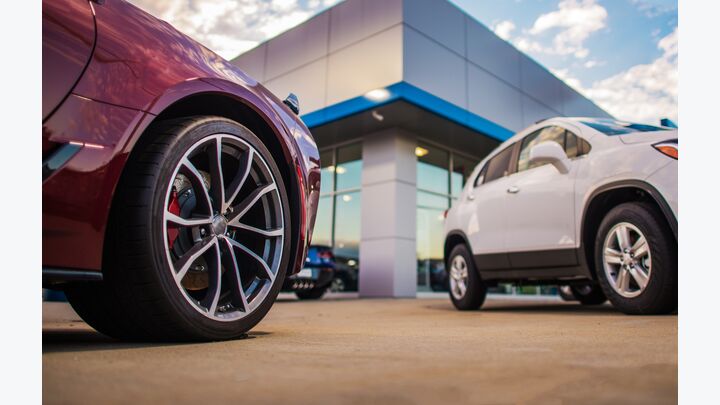 Automotive Dealership Store. New and Pre Owned Vehicles in Front of the Showroom Building.