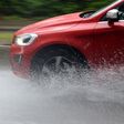 Car splashes trough water on a partly flooded road.
