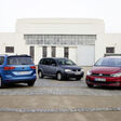 Drei VW Touran Fahrzeuge in Blau, Grau und Gelb vor einem Haus mit großer Tür.