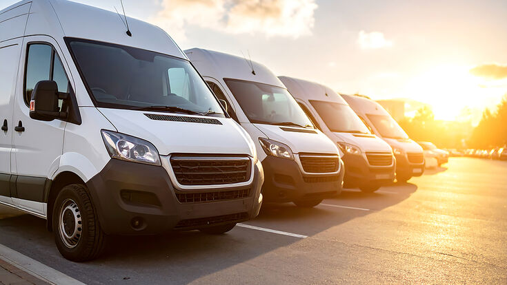 White delivery vans parked in a row at sunset