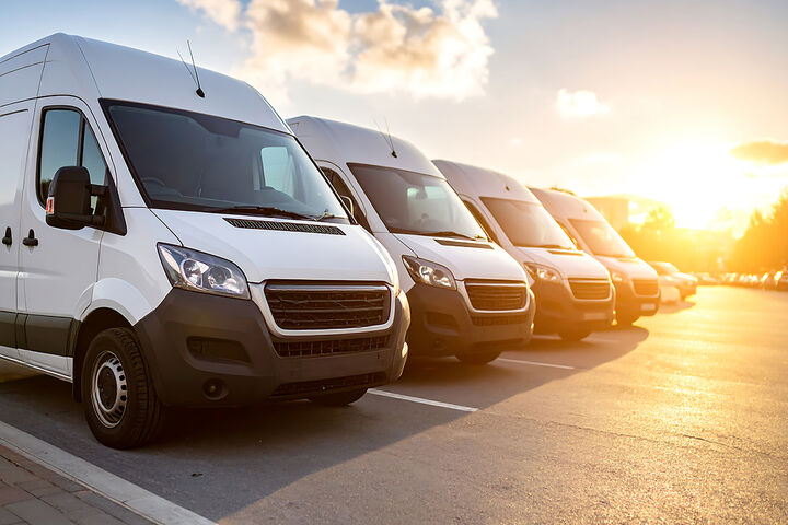 White delivery vans parked in a row at sunset